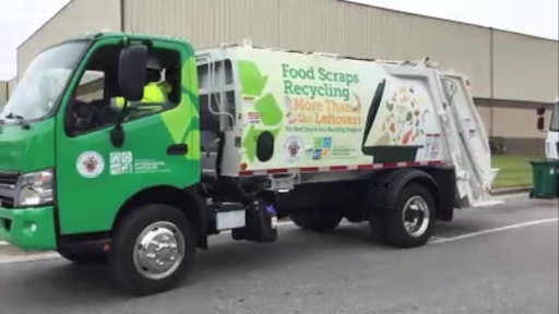 A green garbage-pickup-style truck that on the side says "Food Scrap Recycling," with a recycling symbol and the Montgomery County logo.