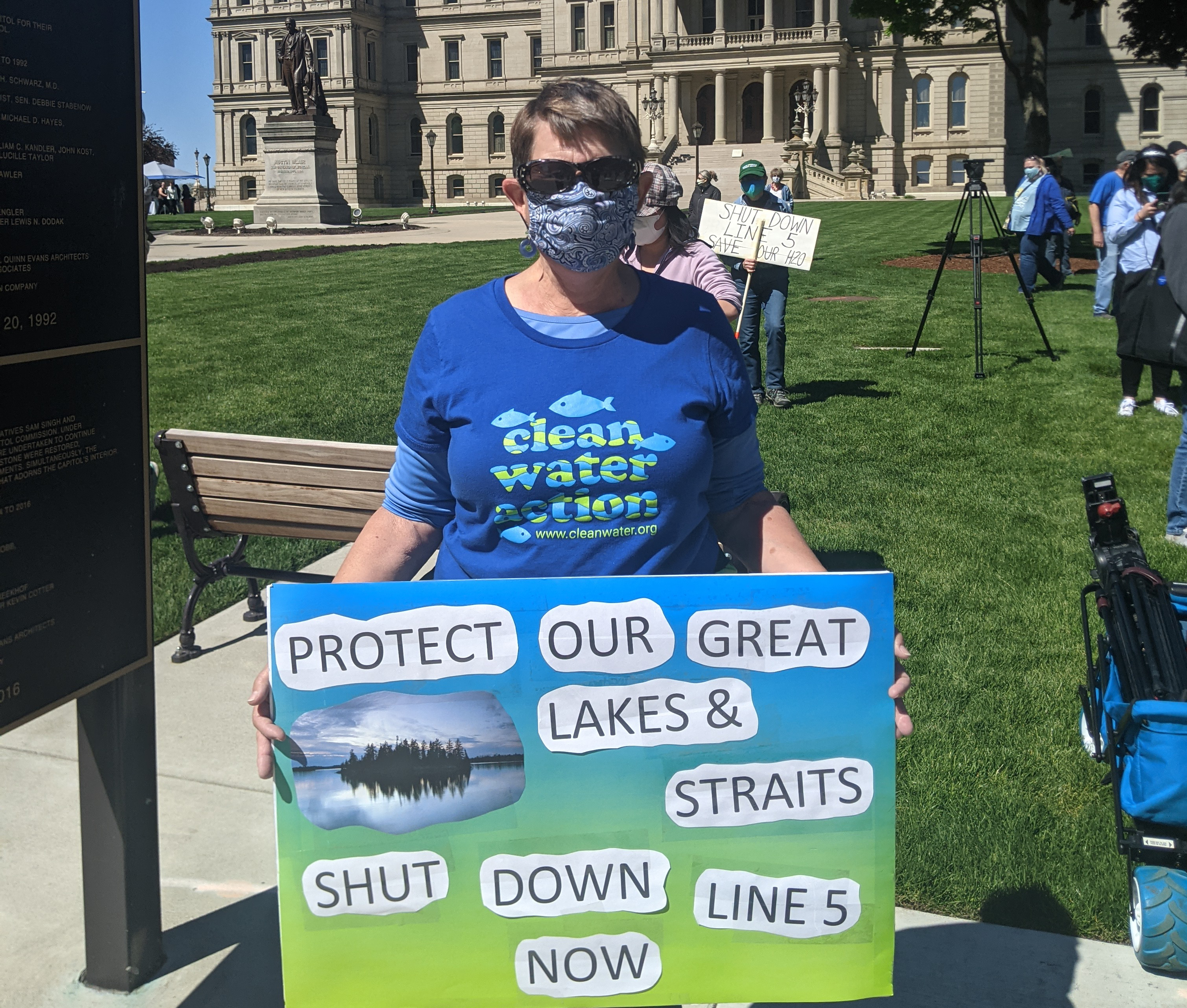 Protestor outside Michigan Capitol wearing Clean Water Action shirt and sign saying Protect our Great Lakes and Straits Shut Down Line 5 Now