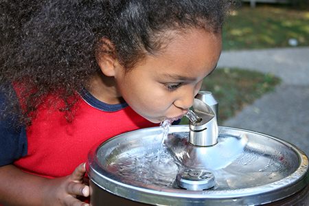 Young girl drinking from a water fountain Young girl drinking from a water fountain