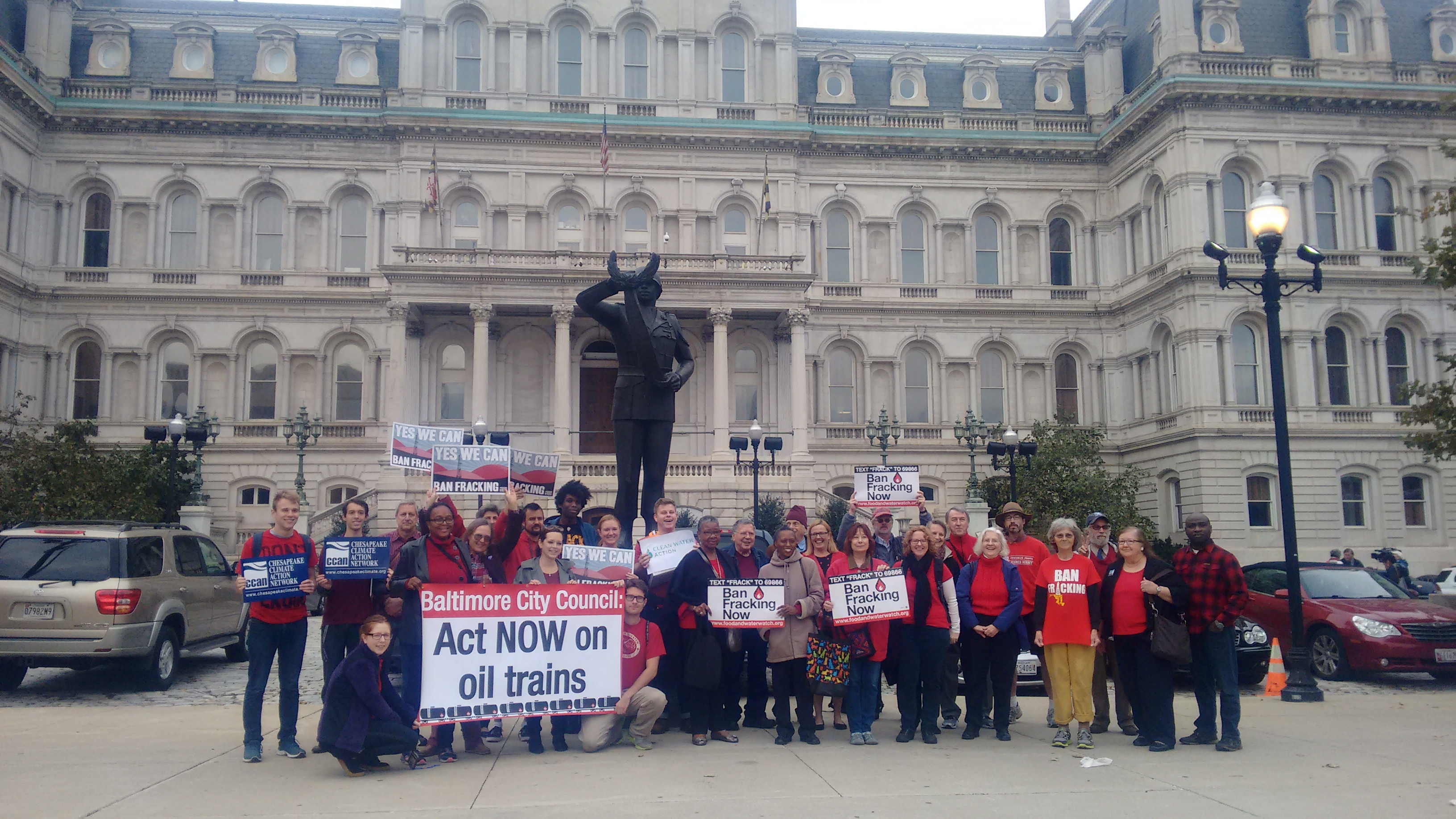 Over 30 Baltimore residents outside of City Hall wearing red in support of the Oil Trains Ordinance