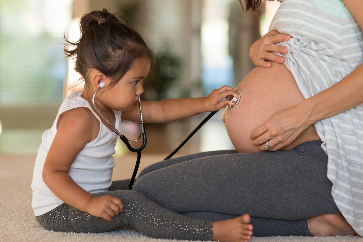 toddler with stethoscope listening to pregnant belly. photo: istock