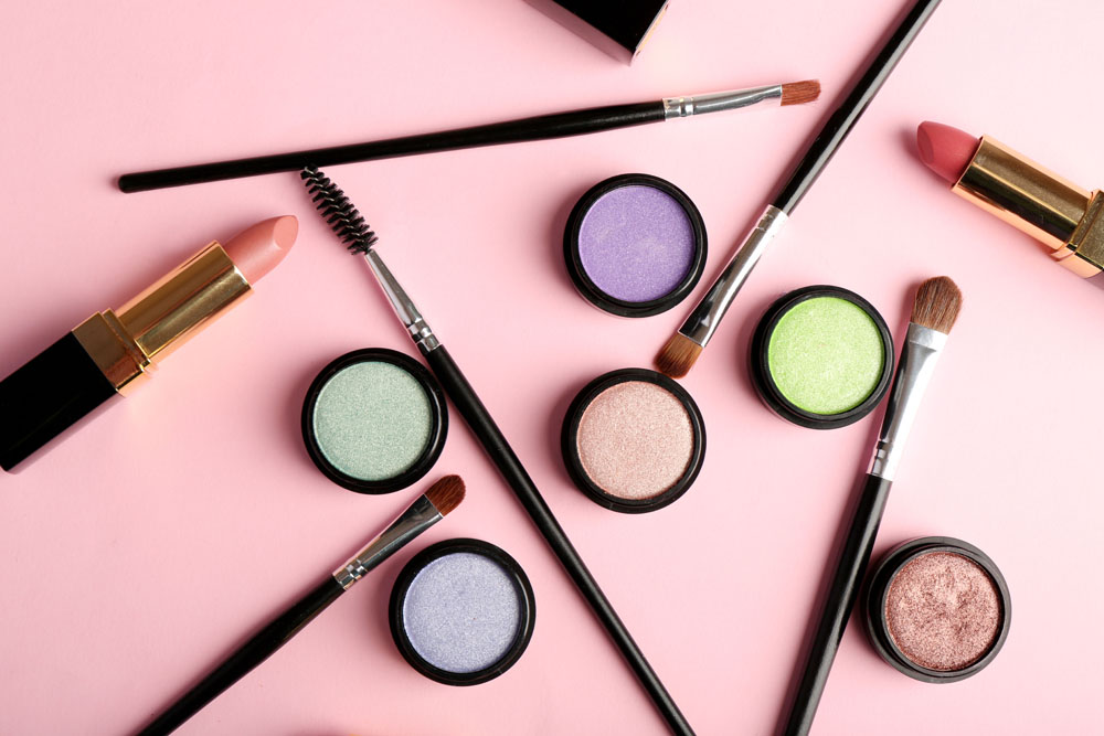 Cosmetics - lipstick, other makeup - arranged on a table. Photo credit: AfricaStudios / Shutterstock